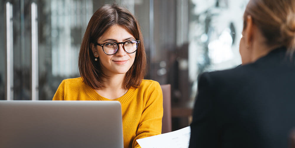 Group of happy business people have meeting at workplace in office. Two positive woman working together using modern laptop for working concept